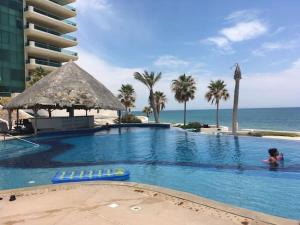 a person in a swimming pool next to the ocean at Ocean Wrap Around Oceanfront Balcony at Tessoro in Las Conchas