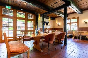 a dining room with tables and chairs and windows at Naturhotel Hof Ehlers in Bergen