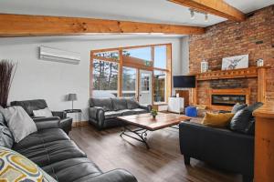 a living room with couches and a brick wall at Birch View- Balcony-Backyard-Parking-Sauna-Sleeps 20 in Blue Mountains