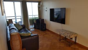 sala de estar con sofá y TV de pantalla plana en Hermoso Departamento Frente al Muelle Vergara - Viña del Mar, en Viña del Mar