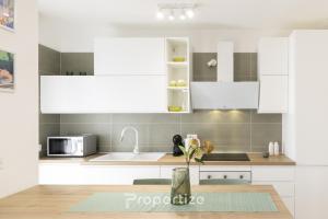 a kitchen with white cabinets and a sink at Verde Appartamento Moderno in Monserrato