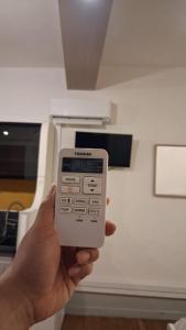 a person holding a remote control in front of an oven at Le Thiers Studio in Auxonne