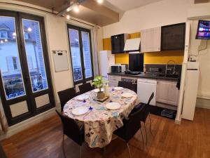 a kitchen with a table with chairs and a tablecloth on it at Le Thiers Studio in Auxonne
