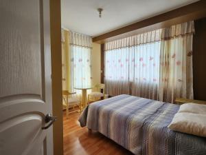 a bedroom with a bed and a window with curtains at Refugio del Lago in Puno