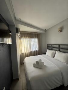 a bedroom with a large white bed with a towel on it at Appart Hotel Bloom in Al Hoceïma +24 photos