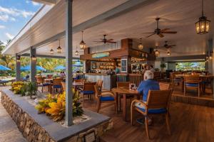 a woman sitting at a table in a restaurant at Palms Resort and Beach in La Grande Princesse