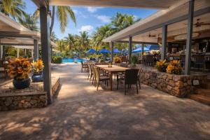 a restaurant with tables and chairs and a pool at Palms Resort and Beach in La Grande Princesse