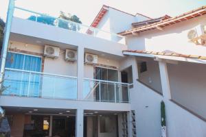 a white apartment building with a balcony at Pousada Porto Maresias in Cabo Frio