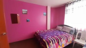a pink room with a bed and a chair at Kenatural in Cajamarca