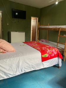a bedroom with a bed with a red blanket on it at Quarto econômico central in Sete Lagoas