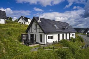 a white house with a black roof on a hill at Landal Winterberg in Winterberg