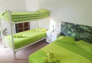 a bedroom with two bunk beds with green sheets at Acuarela Hostal in Playa Blanca