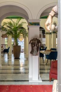 a lobby with a table and a sculpture on a column at Bronlara in Alhaurín de la Torre