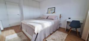 a small bedroom with a bed and a blue chair at Valença Sky View in Valença