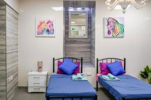 two beds in a room with blue and pink pillows at The Oyster - F in Il-Furjana