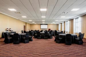 a conference room with tables and chairs and a screen at Four Points by Sheraton Grande Prairie in Grande Prairie