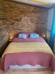 a bedroom with a pink bed with a brick wall at Chalet Majoie in Les Mages