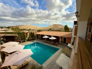a swimming pool with umbrellas and a hotel at Huacachina Desert House in Ica