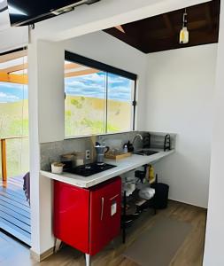 a kitchen with a red stove and a window at Vinhedo Villarejo - Chalés do Vinhedo in Paty do Alferes