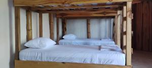 two bunk beds with white sheets in a room at Finca Hostal Eva Maria in Santa Marta