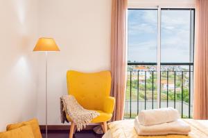 a bedroom with a yellow chair and a window at Casa Nobrega in Caniço