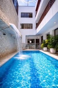 a swimming pool with a waterfall in a building at Hotel Casa Esmeralda in Cali