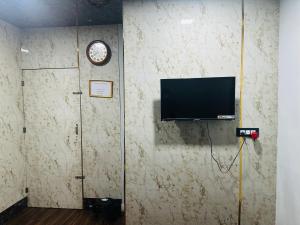 a room with a wall with a clock and a television at Hidden key guest house in Bhubaneshwar
