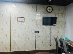 a wall with a clock and a tv on it at Hidden key guest house in Bhubaneshwar