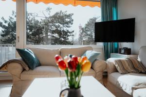 a living room with a couch and a table with flowers at Ferienwohnung Westerlicht - Apartment am Leuchtturm - De Torenhoeve in Nieuw-Haamstede