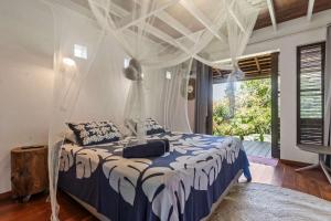 a bedroom with a bed with a canopy at Tropical 2BR Bungalow with Private Pool in Taravao