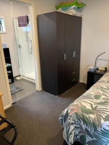a bedroom with a large black cabinet next to a bed at Quiet restful unit with seaviews in Auckland