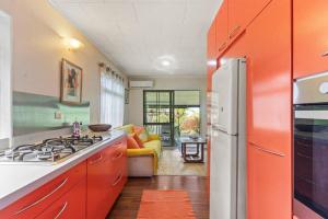 a kitchen with orange cabinets and a white refrigerator at Peaceful 2BR Garden Bungalow in Taravao
