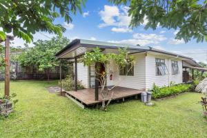 a small white house with a wooden porch at Peaceful 2BR Garden Bungalow in Taravao