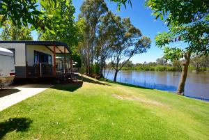 a building on the grass next to a river at Rivergardens Holiday Park Mildura in Gol Gol