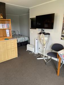 a hotel room with a bed and a desk with a fan at Quiet restful unit with seaviews in Auckland