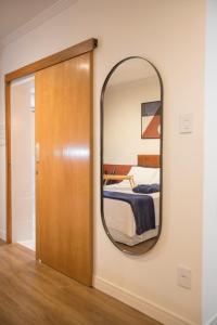 a mirror on a wall next to a bedroom at ApêBrisa73 in São Vicente