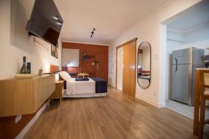 a room with a bed and a kitchen with a refrigerator at ApêBrisa73 in São Vicente
