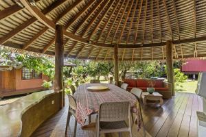 a patio with a table and chairs under a pergola at Charming Tropical Retreat with Private Pool in Taravao
