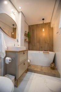 a bathroom with a tub and a sink and a mirror at ApêBrisa73 in São Vicente +19 photos
