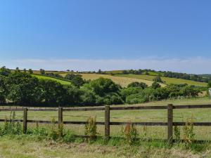 a wooden fence in a field with trees and grass at Shire Cottage - Uk50029 in Liskeard +1 photo