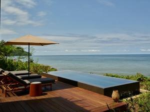 a swimming pool and an umbrella on a deck with the ocean at Rosewood Mandarina in Monteón