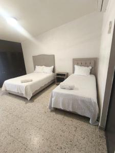 two beds in a room with white sheets and pillows at Casa 25 Centrica con 3 recamaras in Hermosillo
