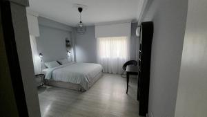 a white bedroom with a bed and a window at Beach apartments in Limassol