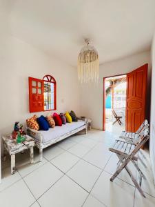 a living room with a couch with colorful pillows on it at Suítes Xicabacana in Mata de Sao Joao