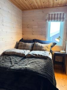 a bed in a room with a wooden wall at Panoramahytte in Norheimsund