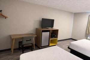 a hotel room with a tv and a desk with a bed at Days Inn by Wyndham Amherst OH - Near Cleveland Cedar Point & Lake Erie in Amherst
