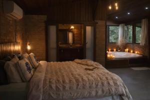 a bedroom with a large bed with a mirror and a tub at Pousada Irreplaceable in Visconde De Maua +60 photos