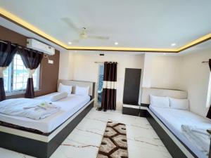 two beds in a room with two windows at BN Hotel in kolkata