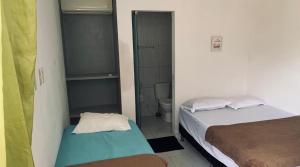 a small room with two beds and a toilet at Pousada Camboinha in Cabedelo