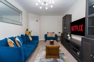 a living room with a blue couch and a tv at Dublin Premier Oasis in Ráth Cúil